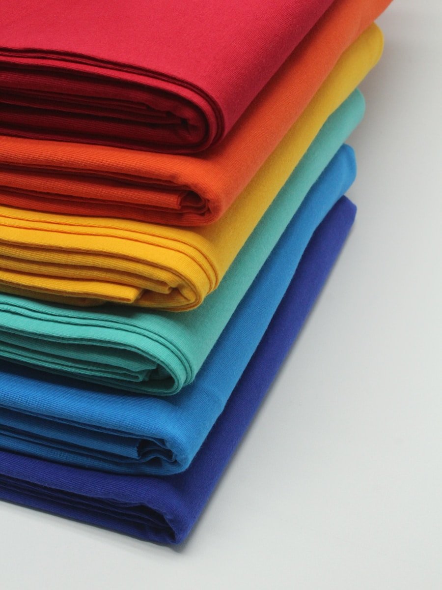 Textiles Margullón Badajoz a stack of bright colored cloths on a white surface
